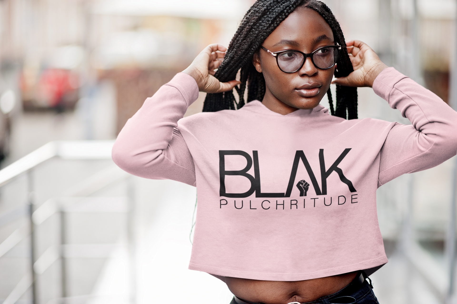Black woman in a cropped black BLVK Pulchritude hoodie, exuding confidence and elegance with wild twist-out curls and quiet power.