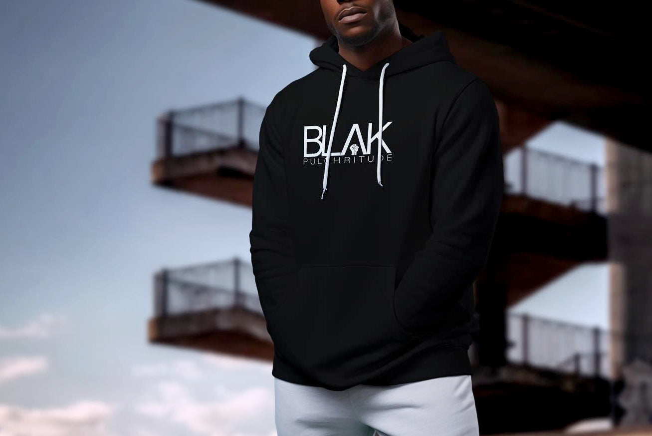 Black man wearing a black BLVK Pulchritude hoodie, standing confidently in an urban setting.